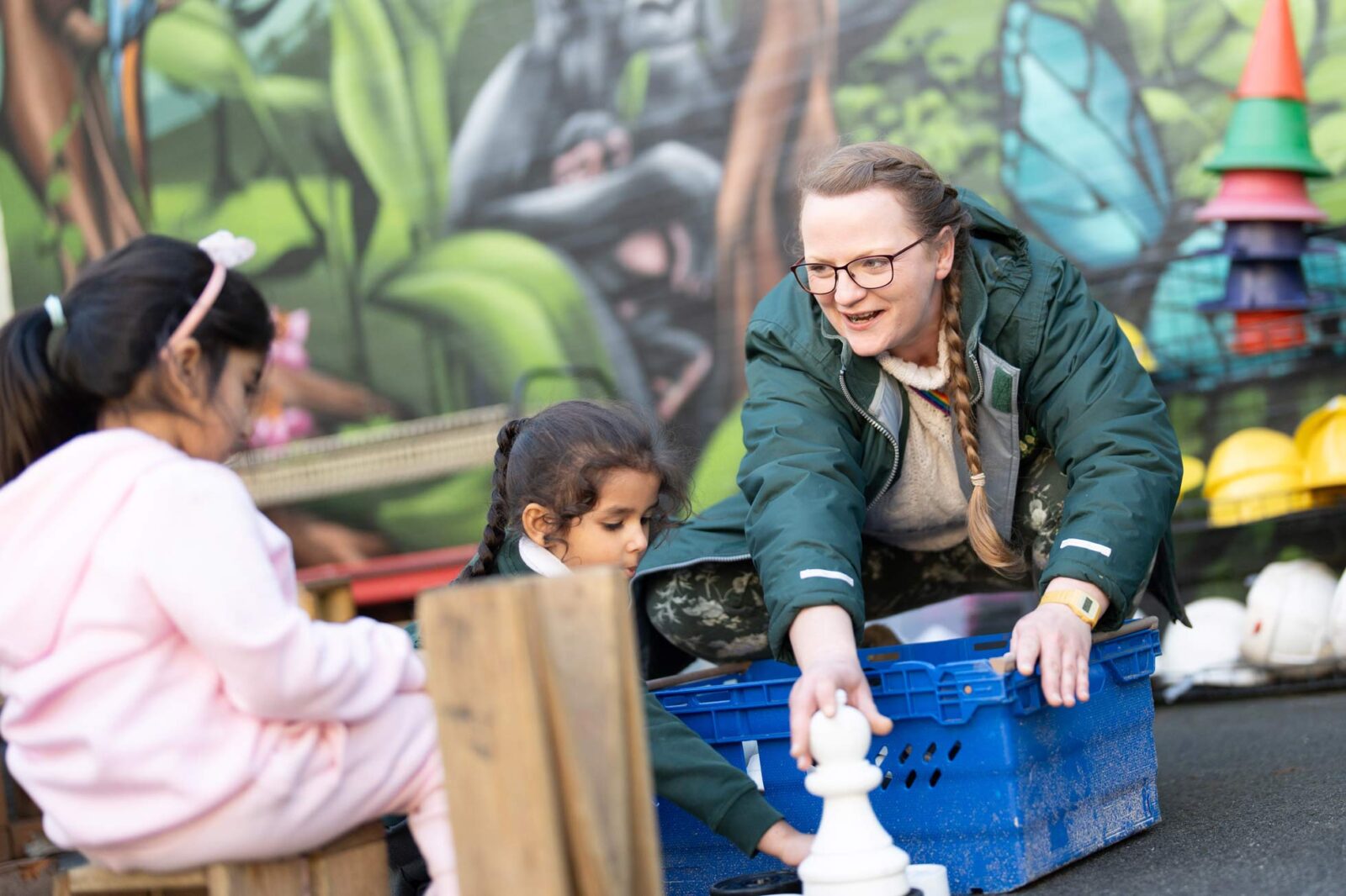 Teacher in the playground with 2 other student sitting on the floor